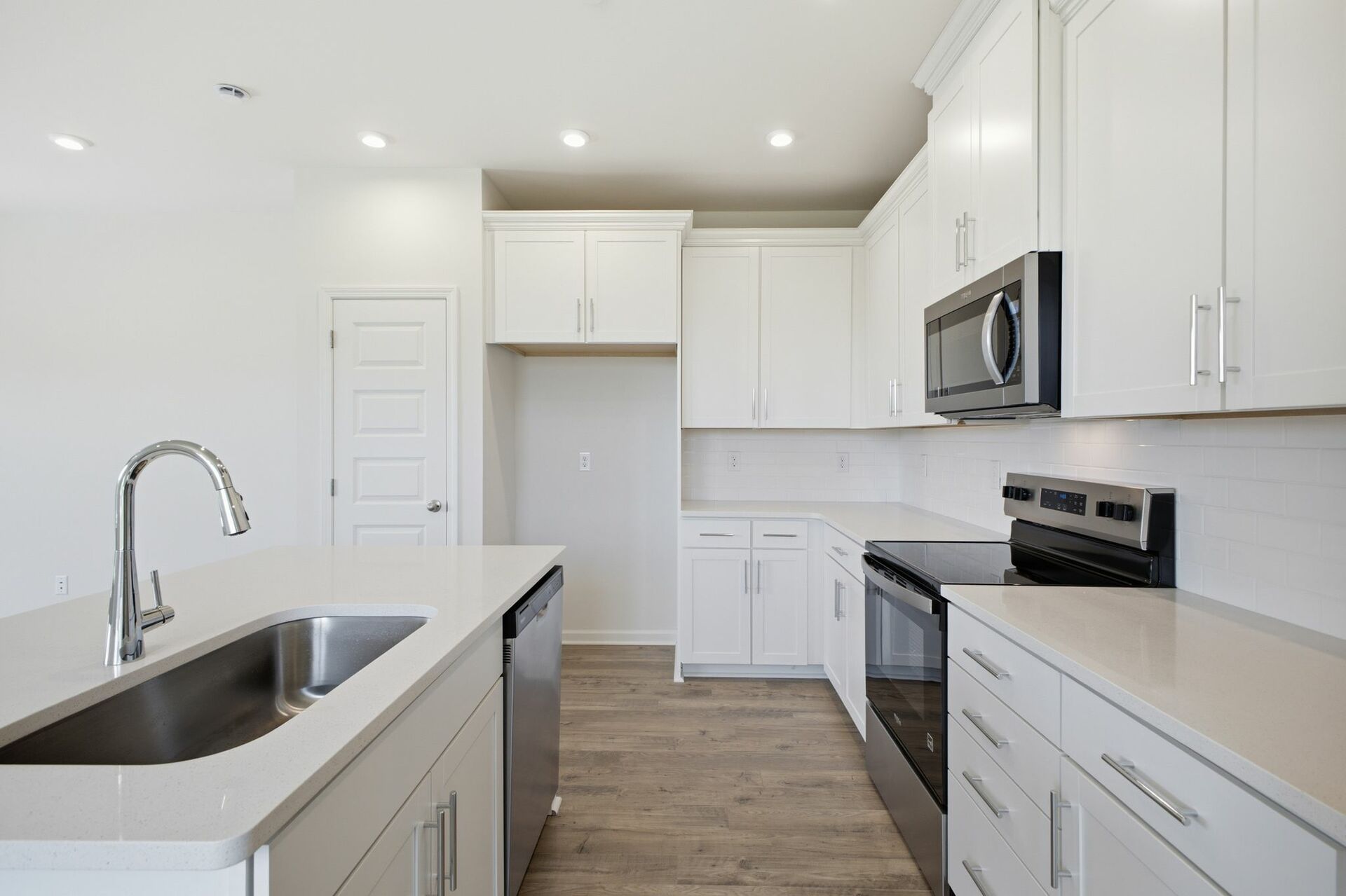 kitchen with white cabinets and counters, wood floors, and stainless steel appliances