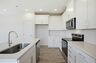 kitchen with white cabinets and counters, wood floors, and stainless steel appliances