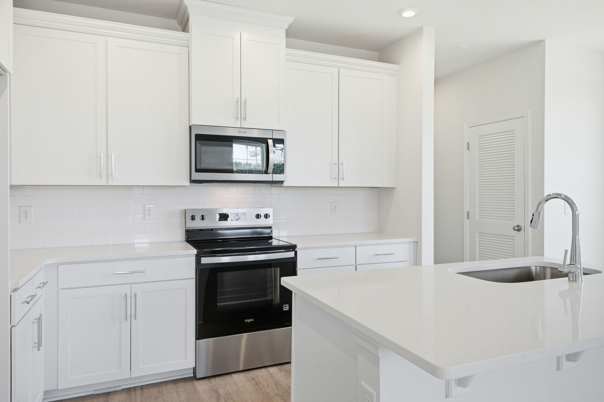kitchen with white cabinets and counters, wood floors, and stainless steel appliances