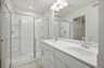 primary bathroom with oversized walk-in shower, dual sink vanity with white counter, white cabinets, and chrome hardware
