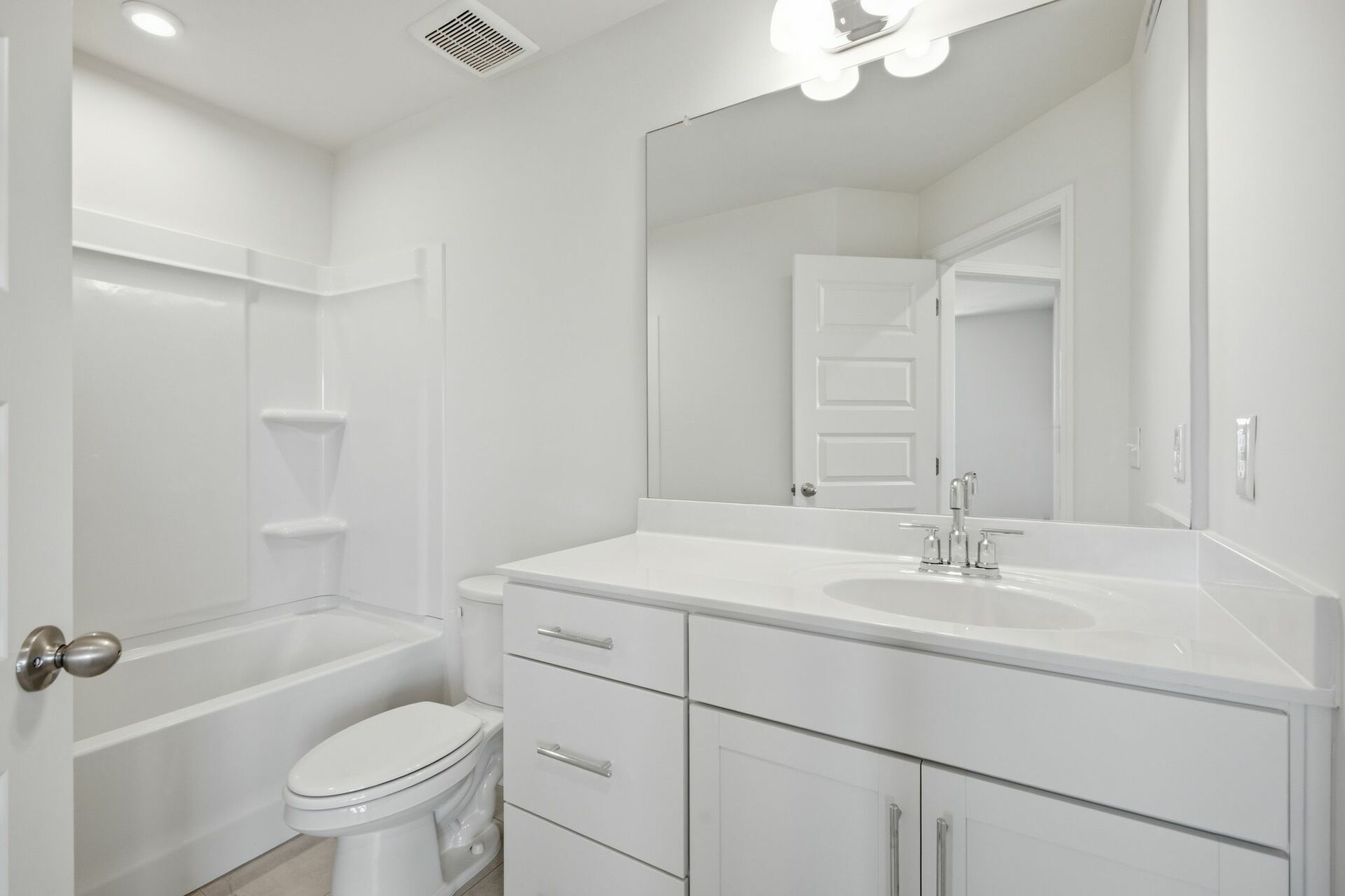 secondary bathroom with large tub, single-sink vanity with white counters and cabinets, polished chrome hardware