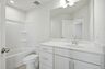 secondary bathroom with large tub, single-sink vanity with white counters and cabinets, polished chrome hardware