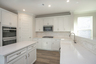 kitchen with gas stove, built in microwave oven combo, white island, and white cabinets