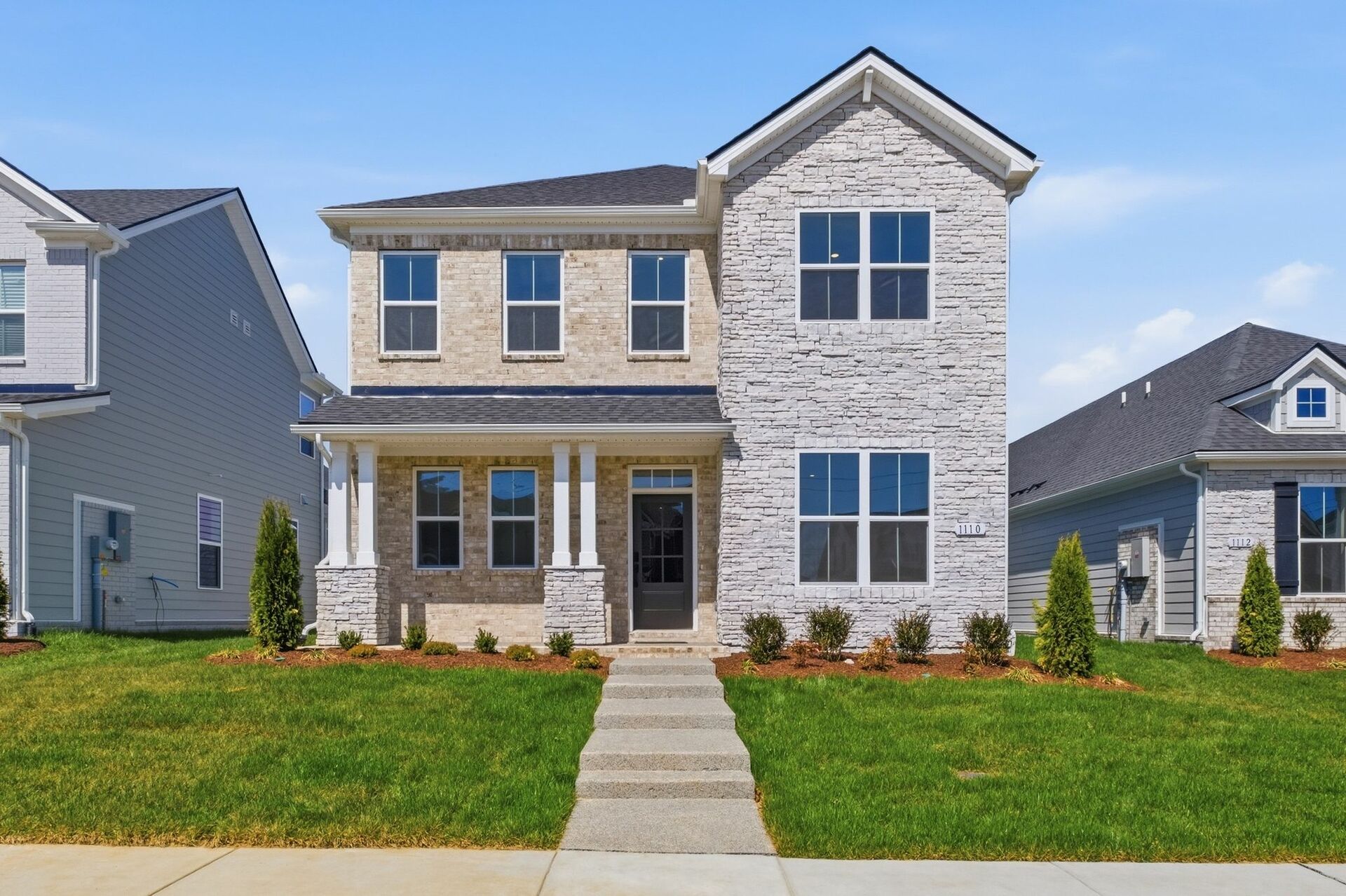 exterior with brick, stone, and a covered front porch