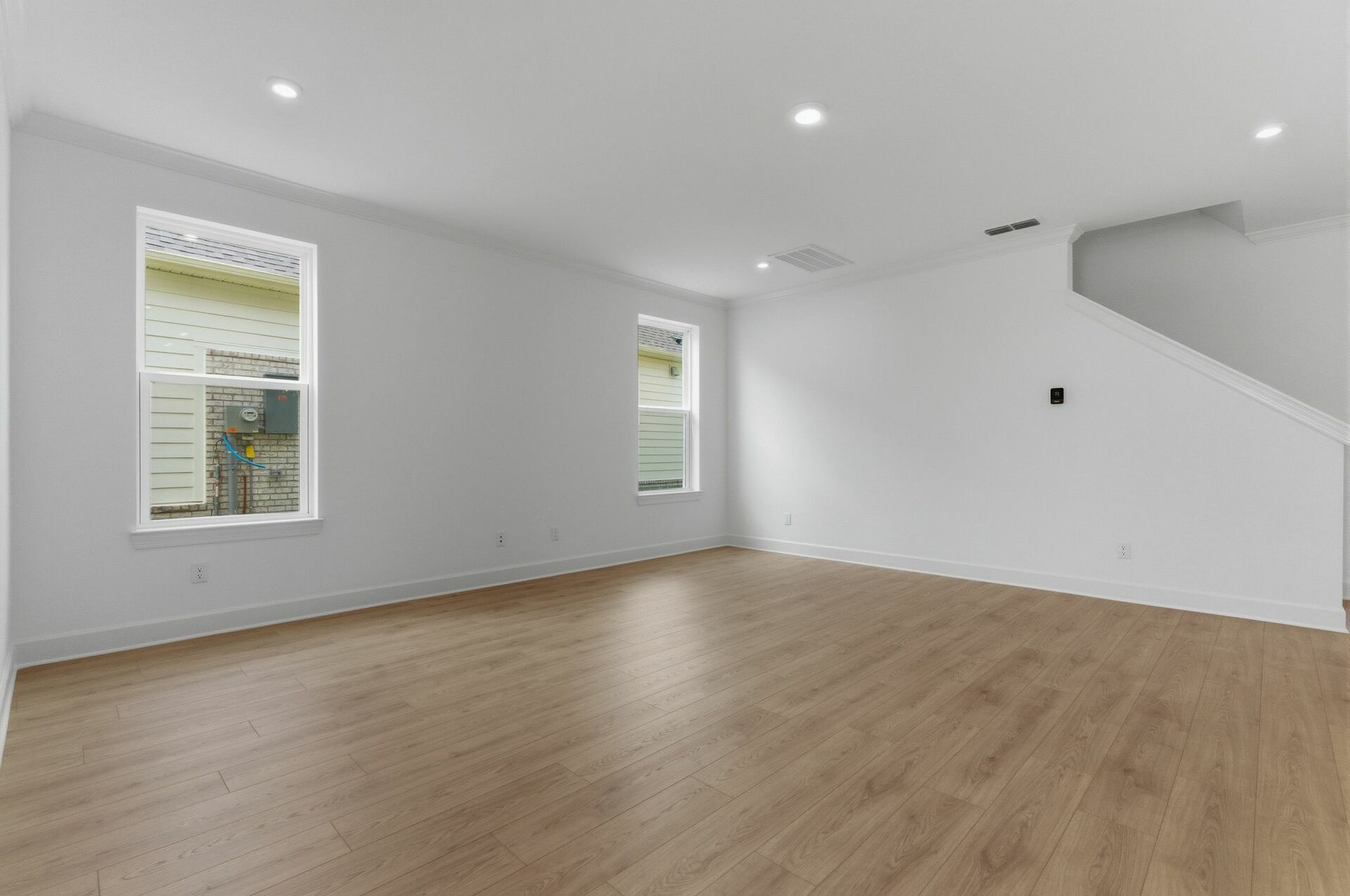great room with light brown wood floors, large windows, white walls and white trim 