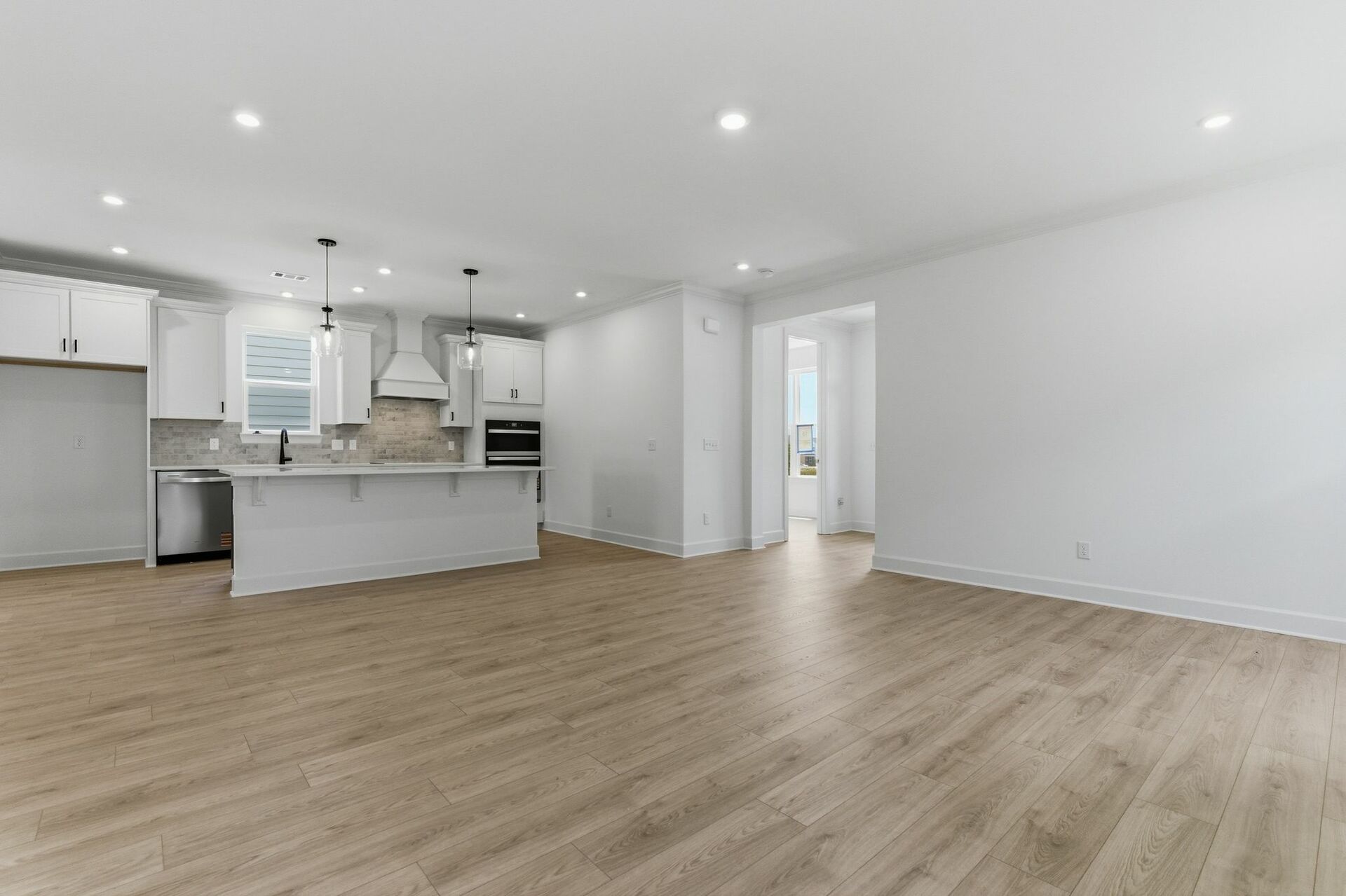 great room with light brown wood floors, large windows, white walls and white trim 