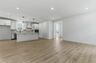 great room with light brown wood floors, large windows, white walls and white trim 