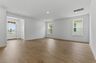great room with light brown wood floors, large windows, white walls and white trim 