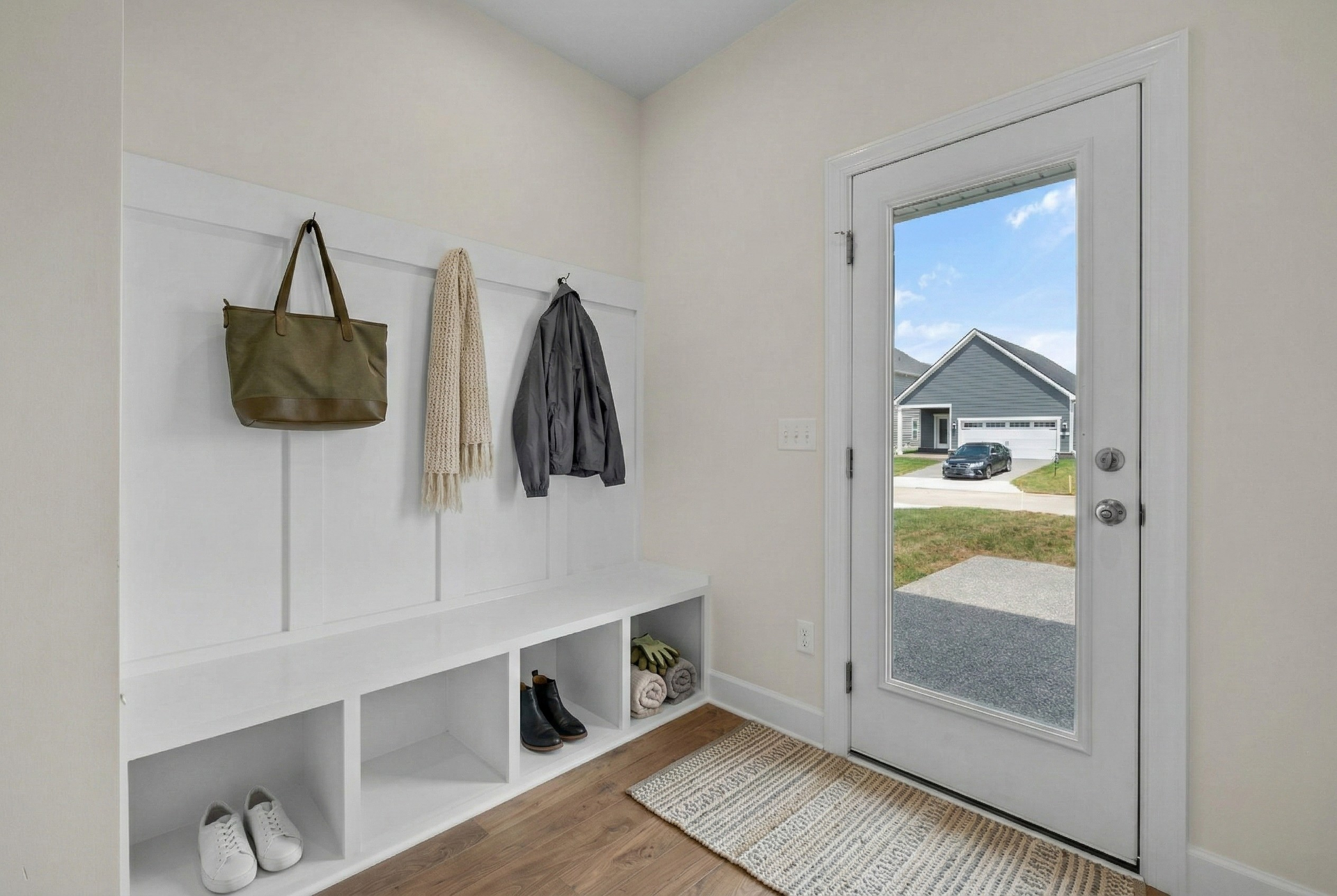 mud room with glass door, wood floors, and a valet bench with hooks