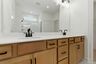 primary bathroom with wood cabinets, dual sink vanity with matte black hardware, and an oversized walk-in shower