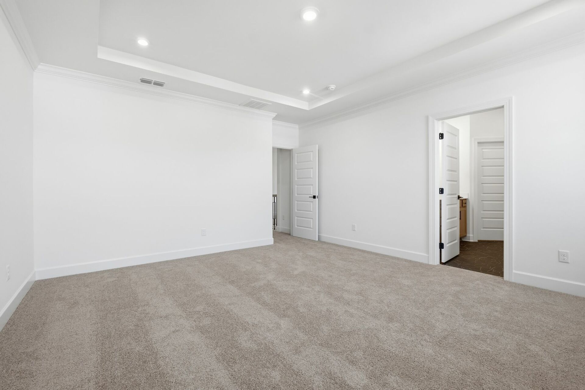 primary bedroom with carpet, tray ceiling, and attached bathroom