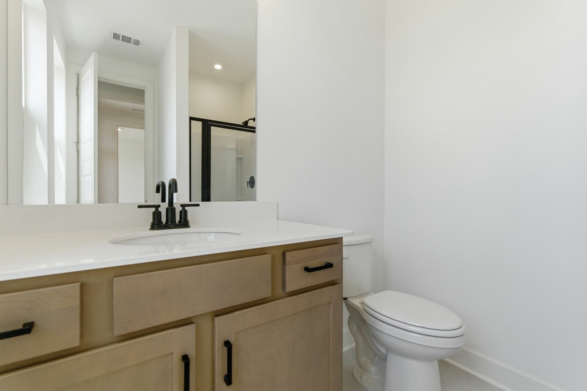 bathroom with wood cabinets and matte black hardware