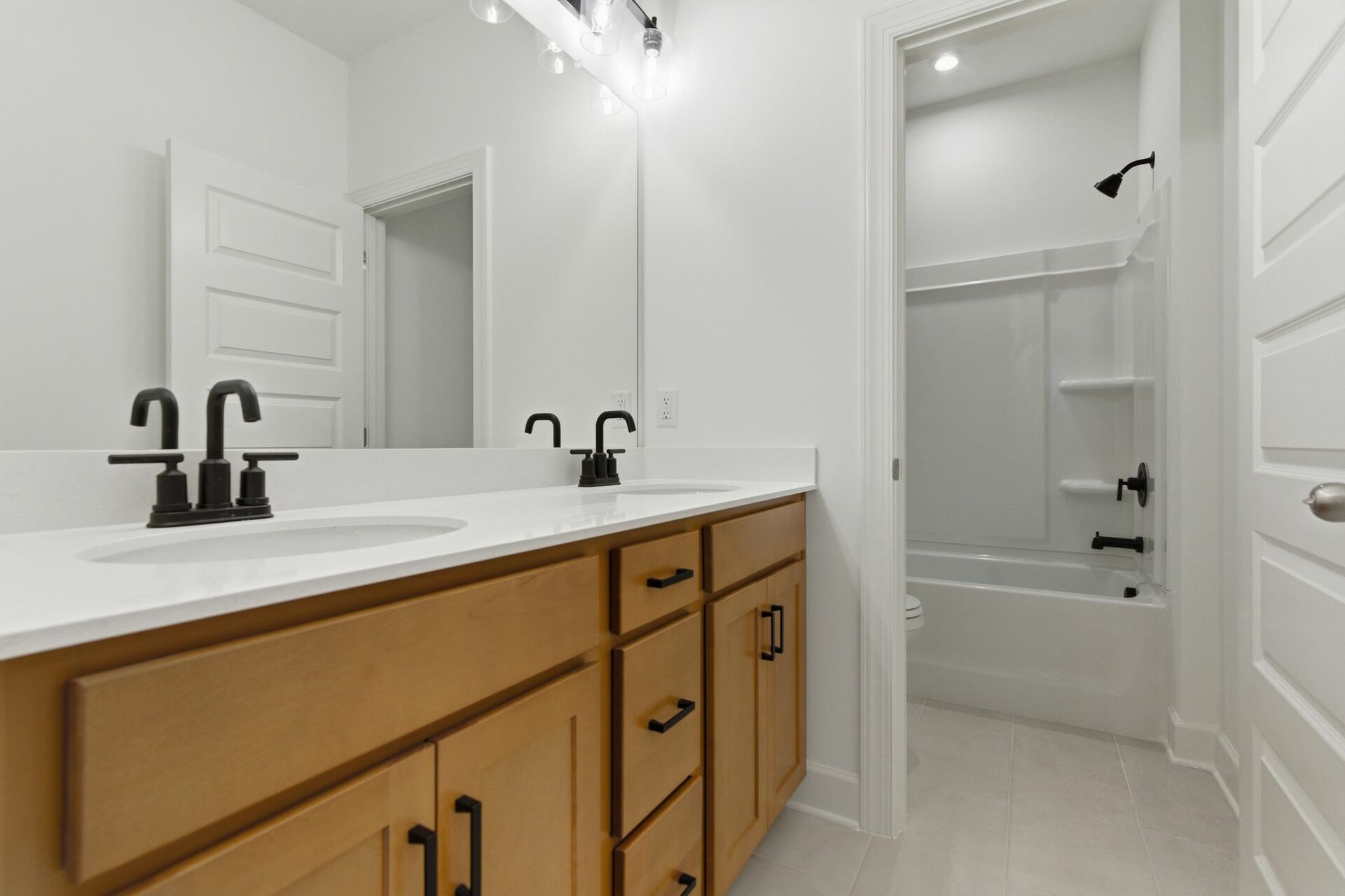bathroom with dual vanity sink, tub, and matte black hardware