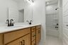 bathroom with dual vanity sink, tub, and matte black hardware