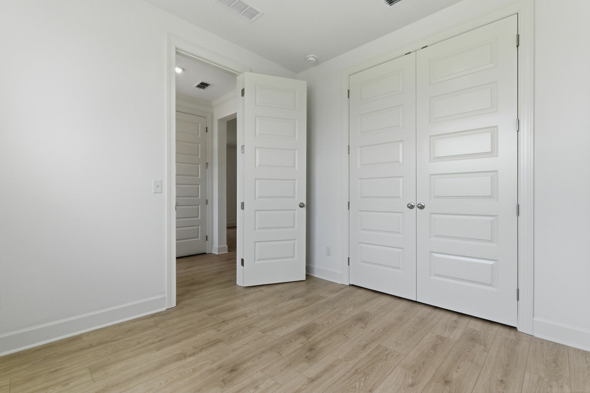 bedroom with light wood floors large windows, and a double door closet