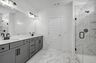 bathroom with marble floors and grey cabinets with double vanity