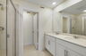 dual sink vanity with a large mirror and shower