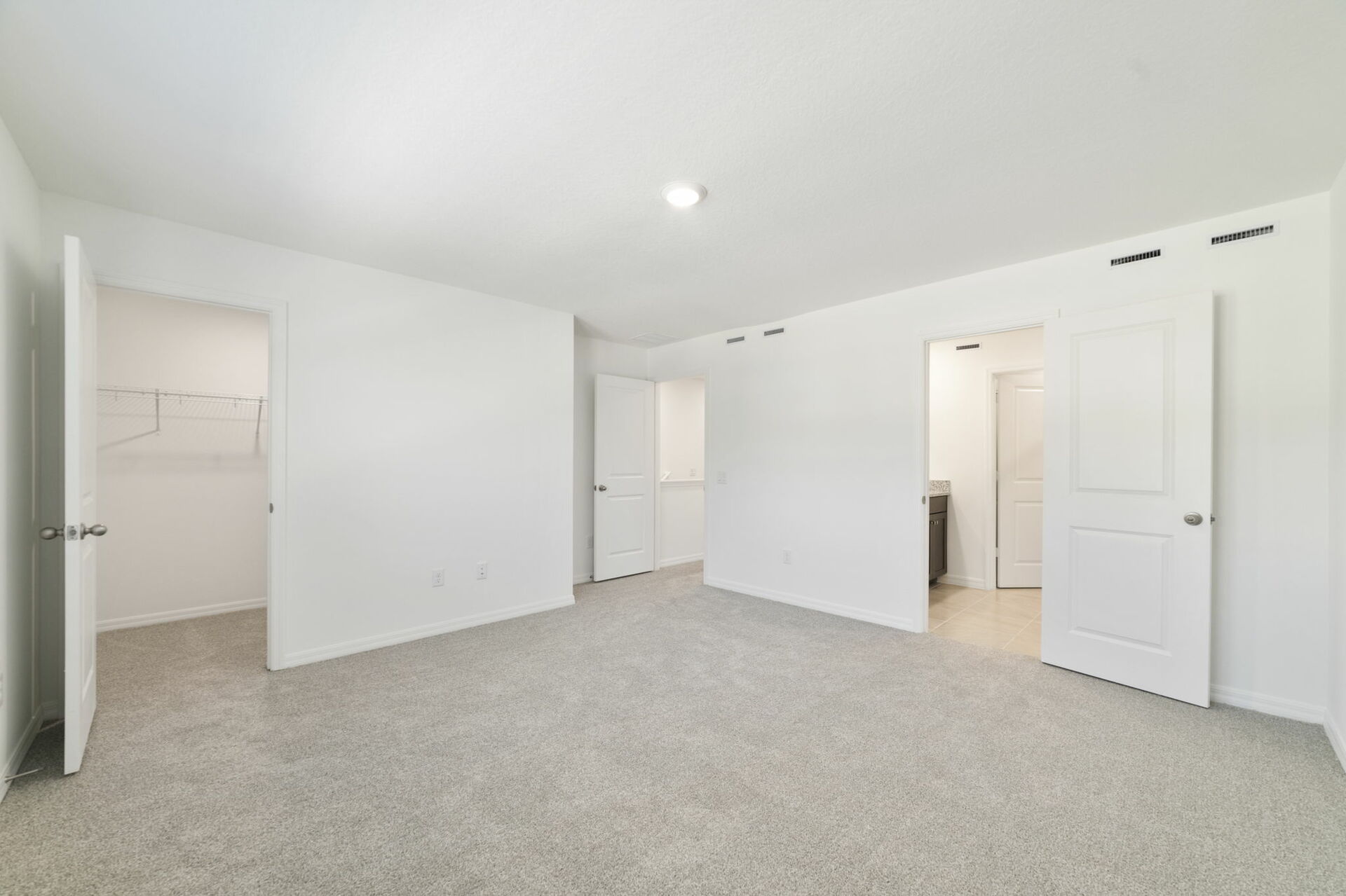 room with carpet throughout and access to the primary bathroom