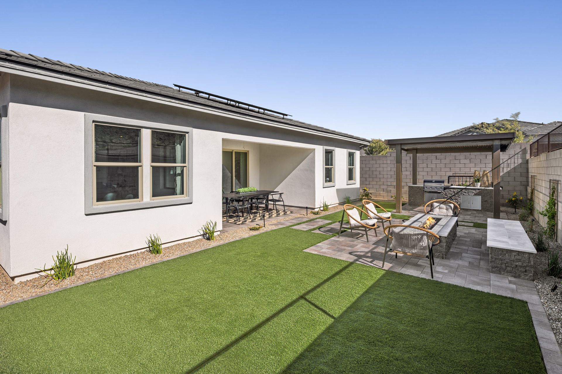 landscaped backyard with artificial grass, gazebo and concrete block wall 