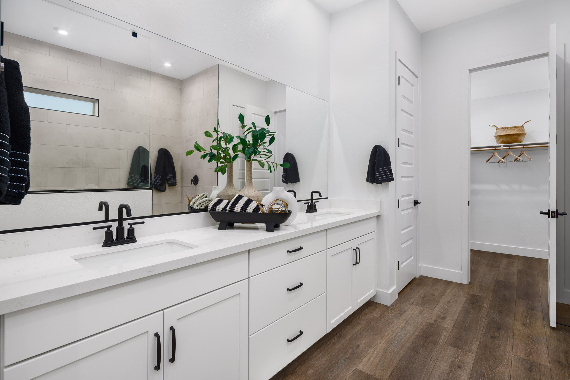 large primary bathroom with white cabinets, double sink, and black hardware