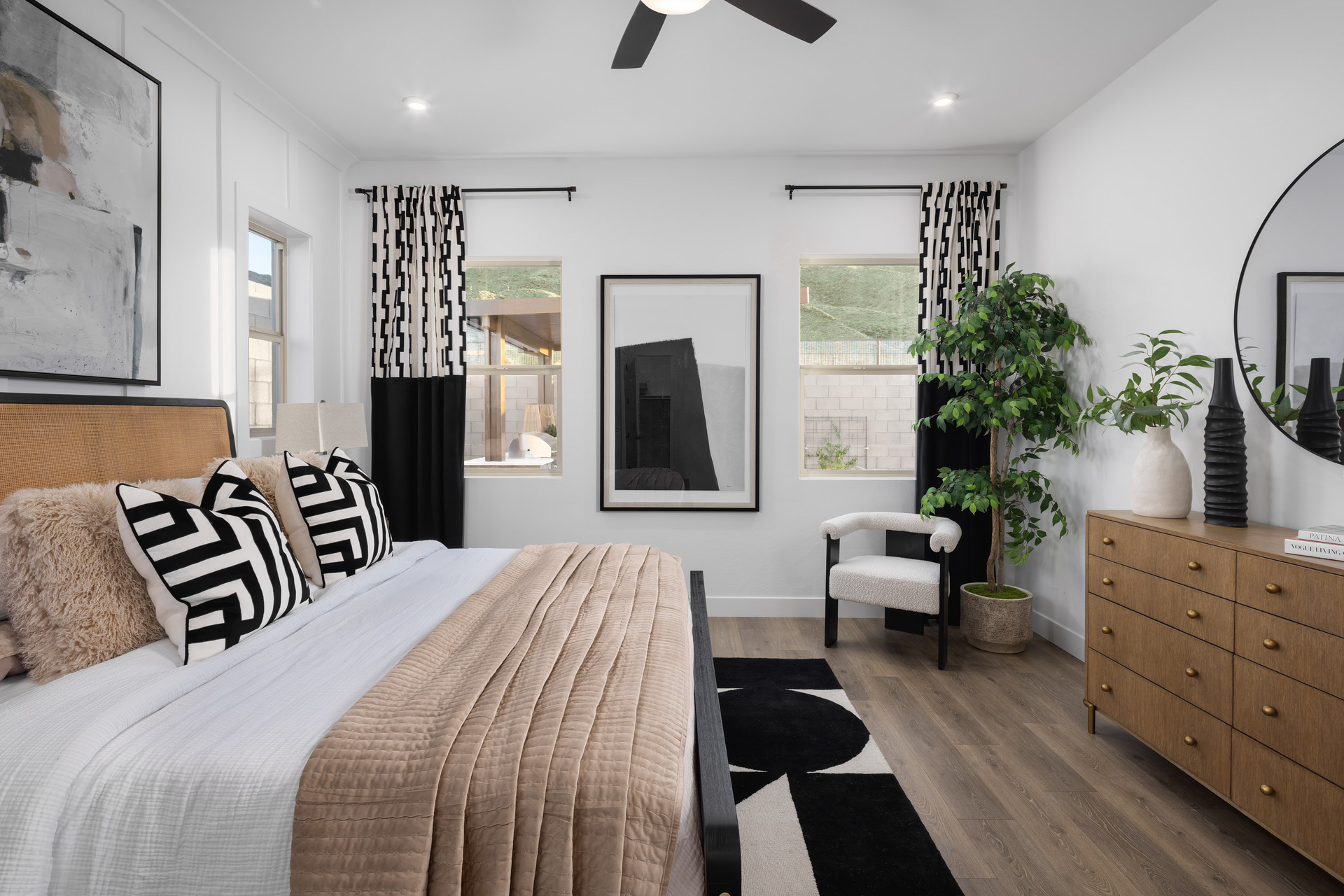 spacious bedroom with a large white bed, white accent chair, and wooden dresser