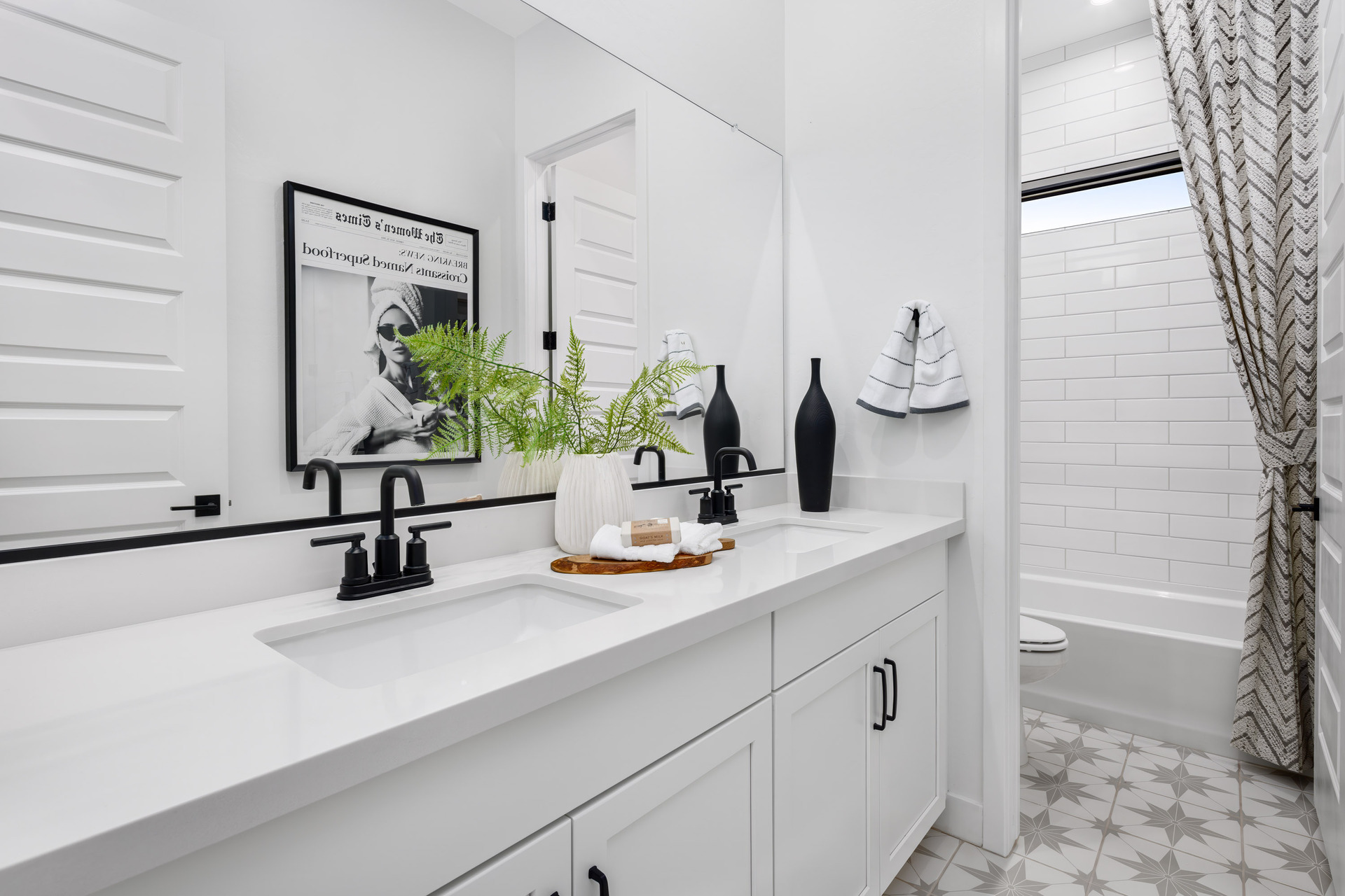 bathroom with white cabinets, double sink, and black hardware