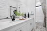 bathroom with white cabinets, double sink, and black hardware
