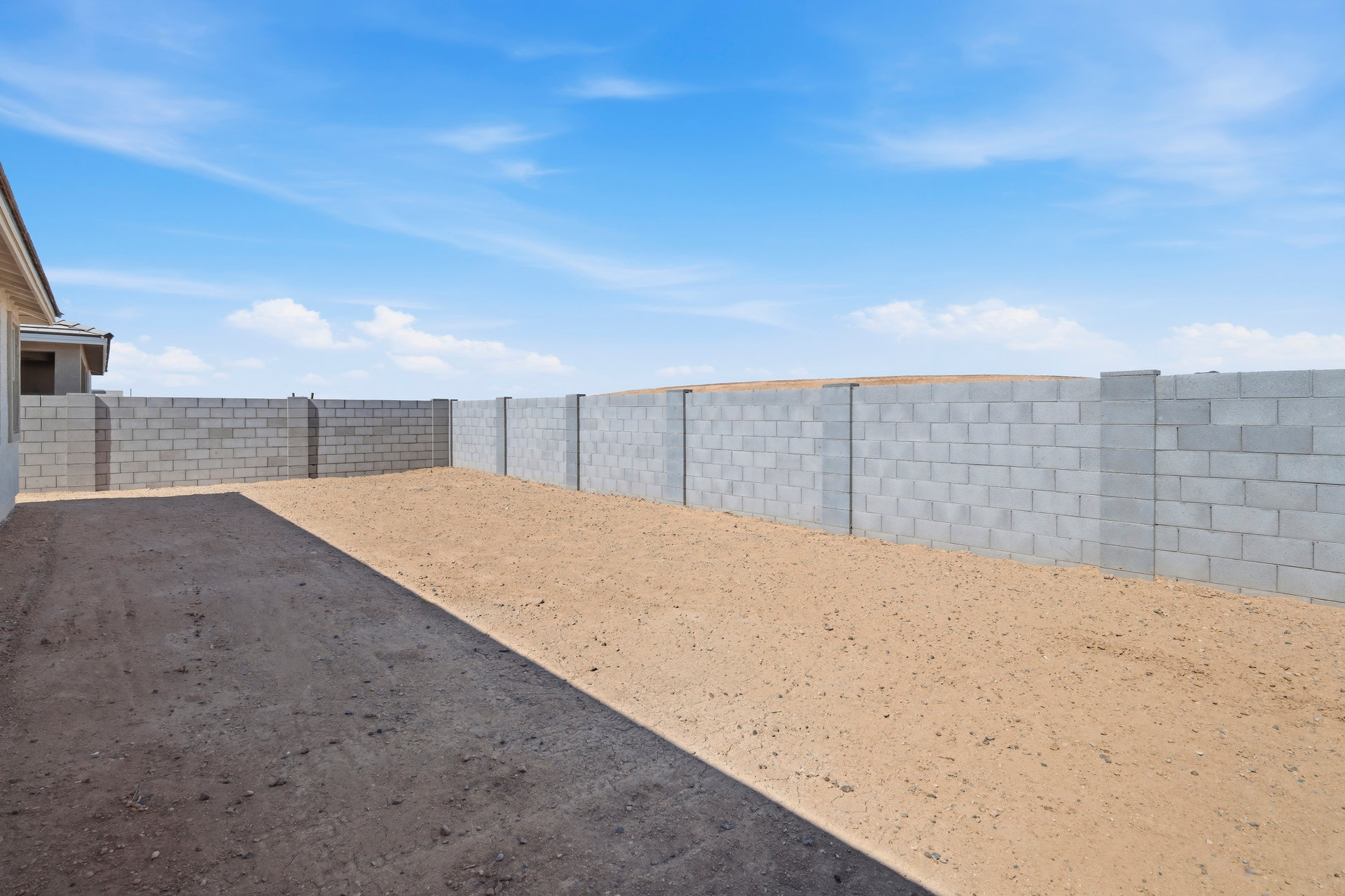 spacious dirt backyard with concrete block wall