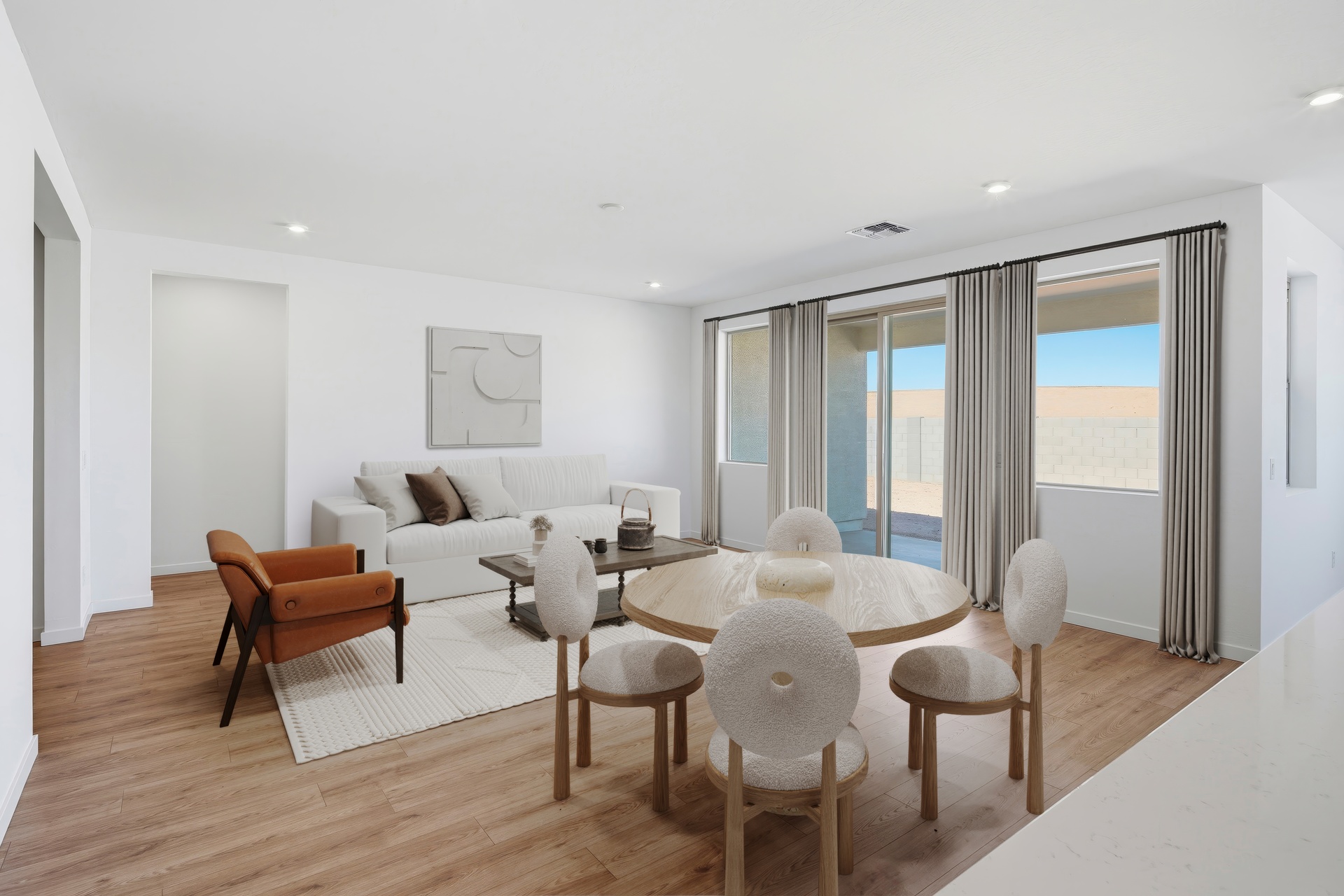 open-concept space with a large white couch, an orange accent chair, and an oak dining table