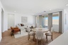 open-concept space with a large white couch, an orange accent chair, and an oak dining table