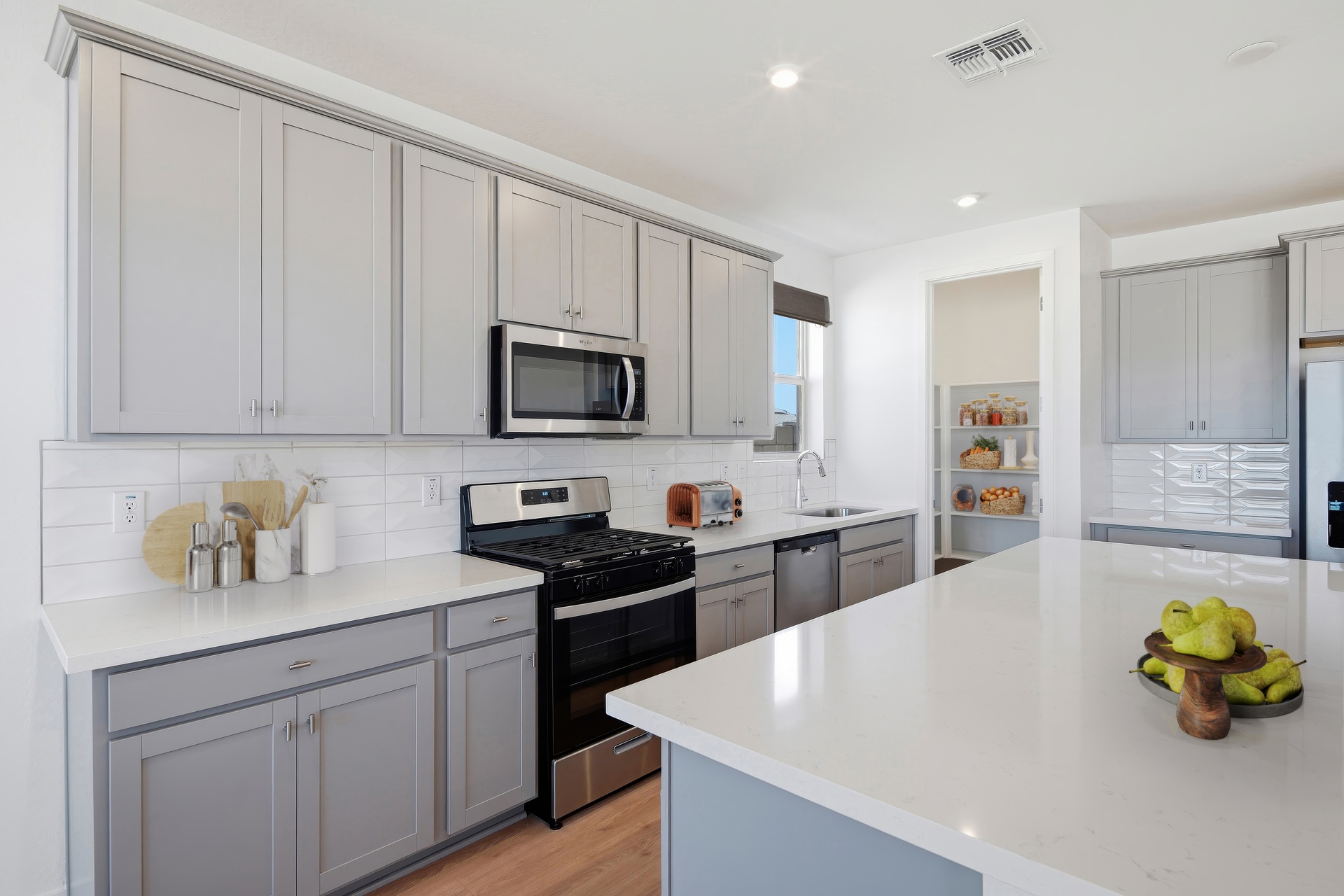 spacious kitchen with grey cabinets, quartz countertops, and stainless-steel appliances