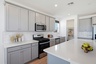 spacious kitchen with grey cabinets, quartz countertops, and stainless-steel appliances