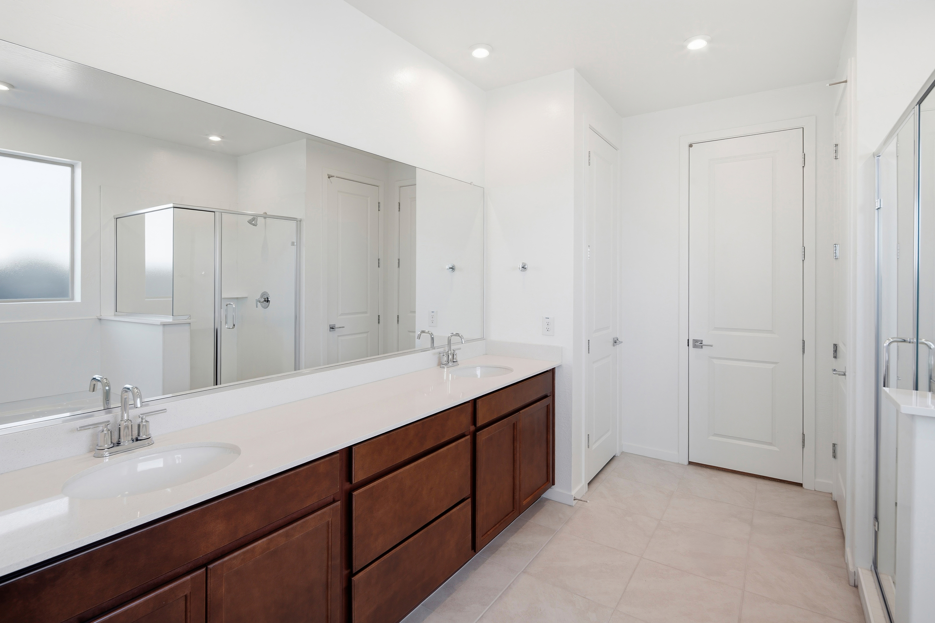 spacious bathroom with brown cabinets, double sink, and chrome faucets