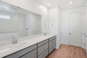 spacious bathroom with grey cabinets, chrome faucets, and white countertop