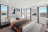 spacious bedroom with a king-sized bed, grey nightstands, and grey/white rug