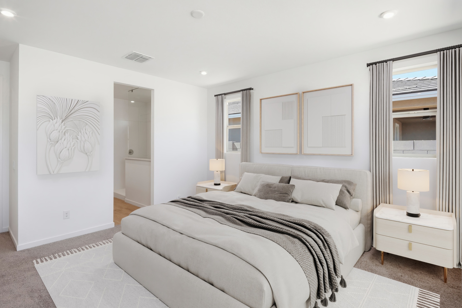 spacious bedroom with a king-sized white bed, a white rug, and white nightstands