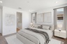 spacious bedroom with a king-sized white bed, a white rug, and white nightstands