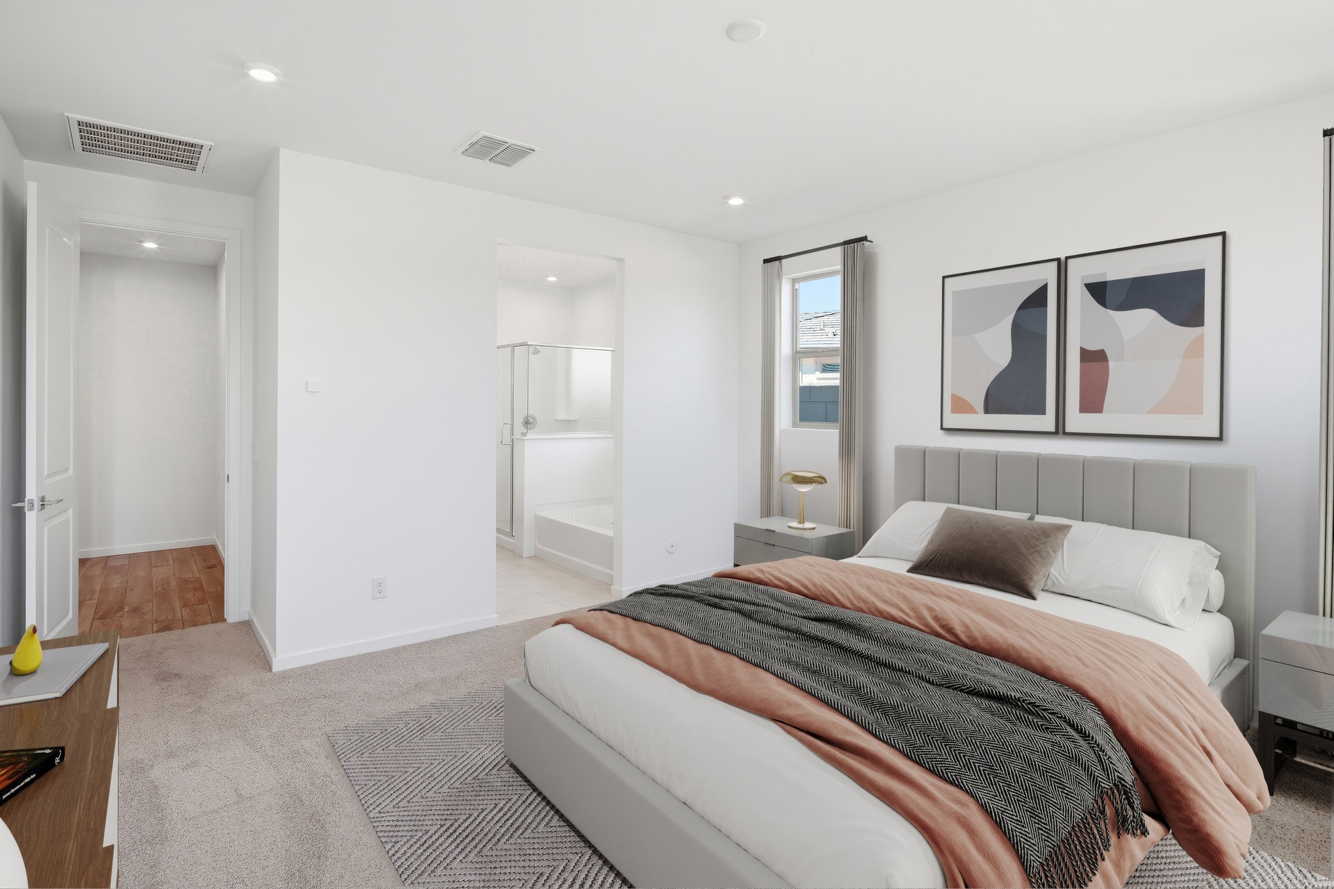 spacious bedroom with a large bed, grey duvet, and grey nightstands.