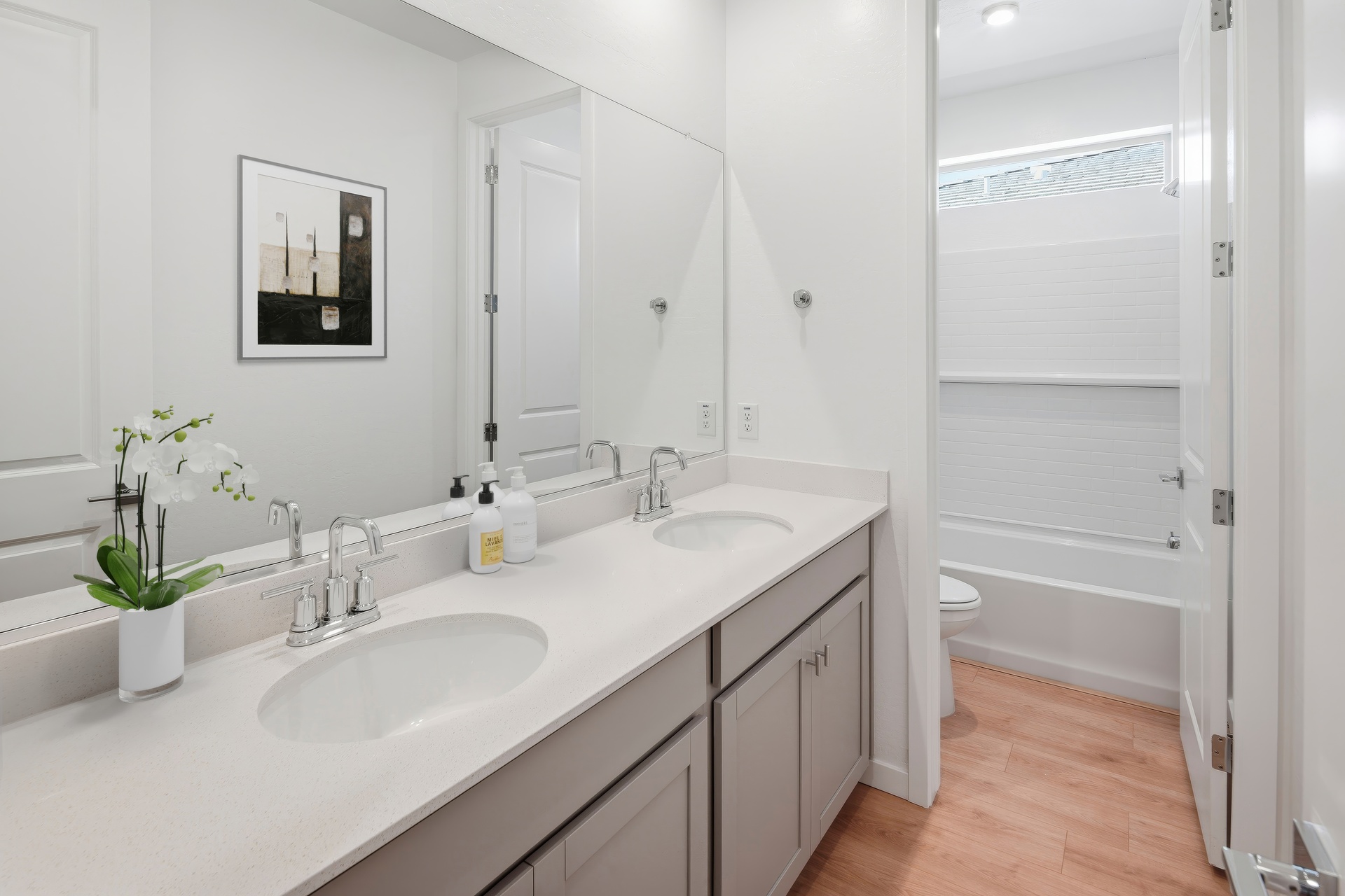 spacious bathroom with grey cabinets, double-sink, and chrome faucets