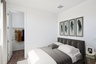 spacious bedroom with a bed, dark grey bedframe, and white rug