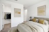 large bedroom with cream-colored bedsheets, yellow pillows, and yellow abstract art