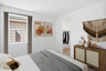 bedroom with a spacious bed with a grey duvet, a dark wooden dresser, and a western-themed aesthetic