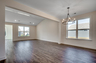 open-concept area with large chandelier, tan walls and dark hardwood flooring throughout  