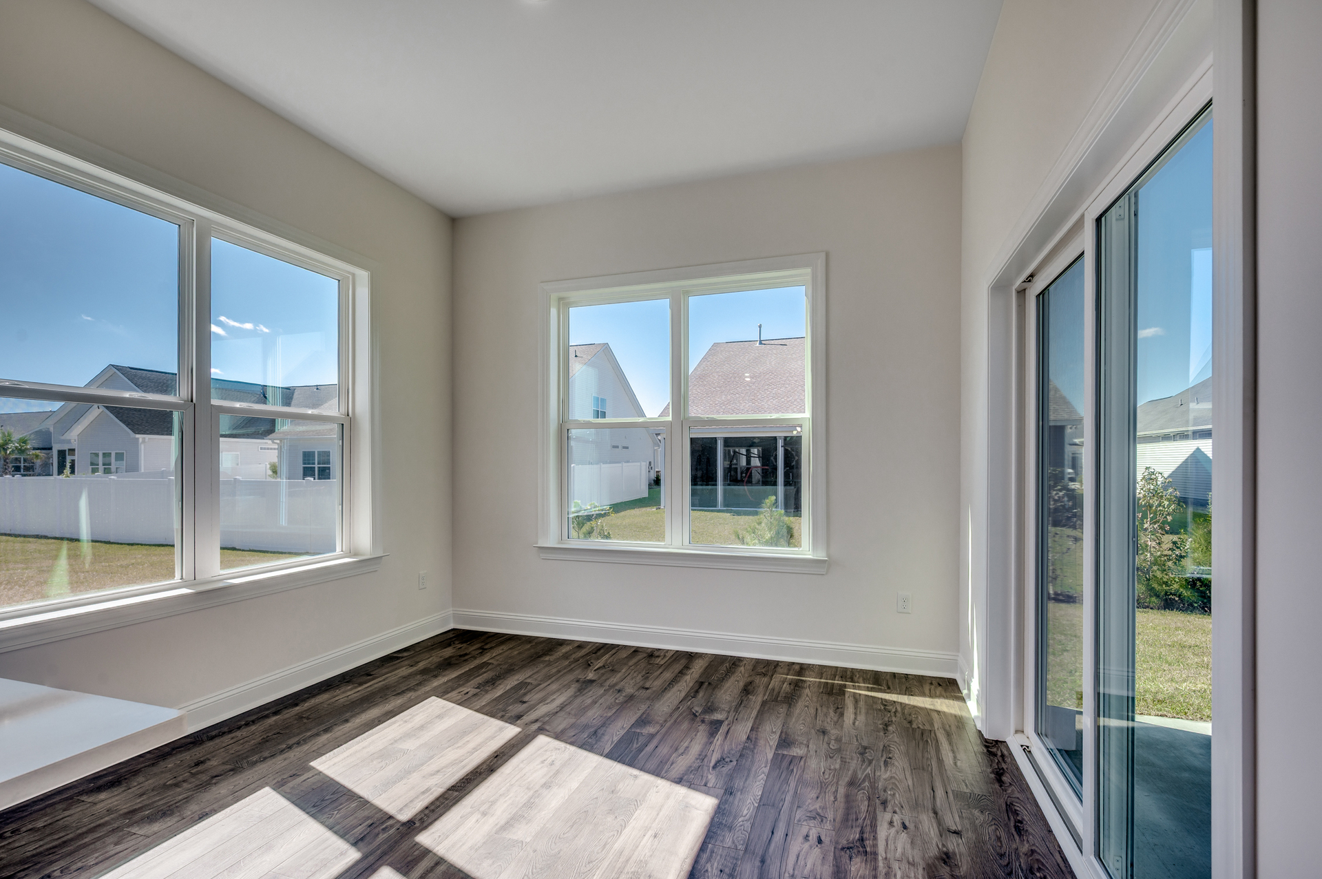 additional room on the rear of home with large windows for natural lighting, large sliding glass door and hardwood flooring 