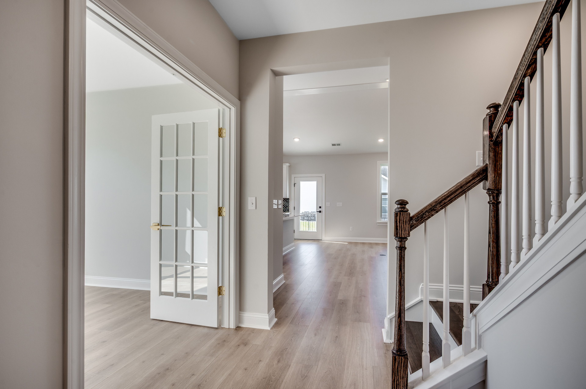 spacious hallway opening up to the study with french doors and the beautiful stairs with dark wood oak treads