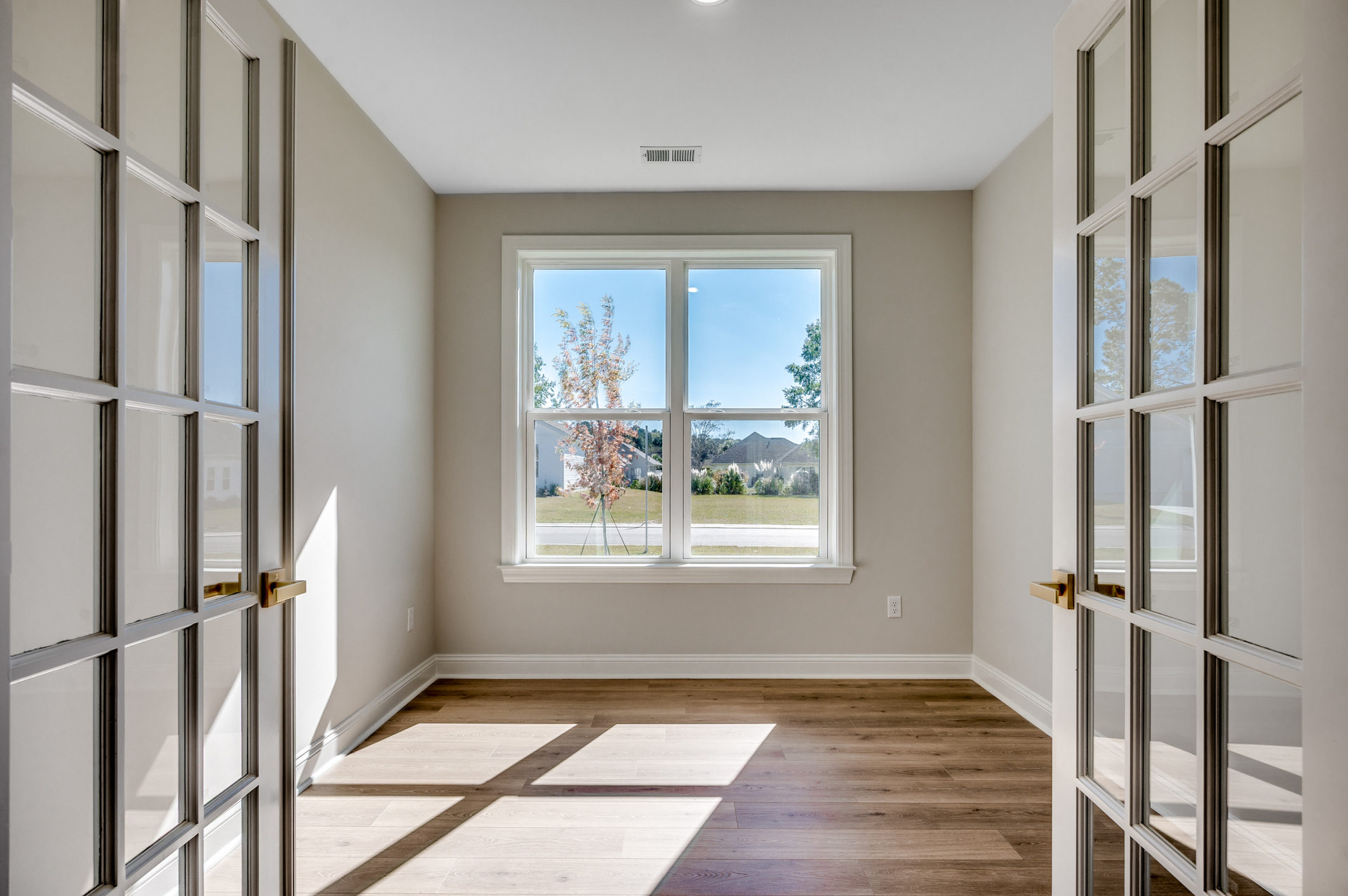 bright room featuring large windows, beautiful hardwood flooring, and elegant glass French doors that fill the space with natural light