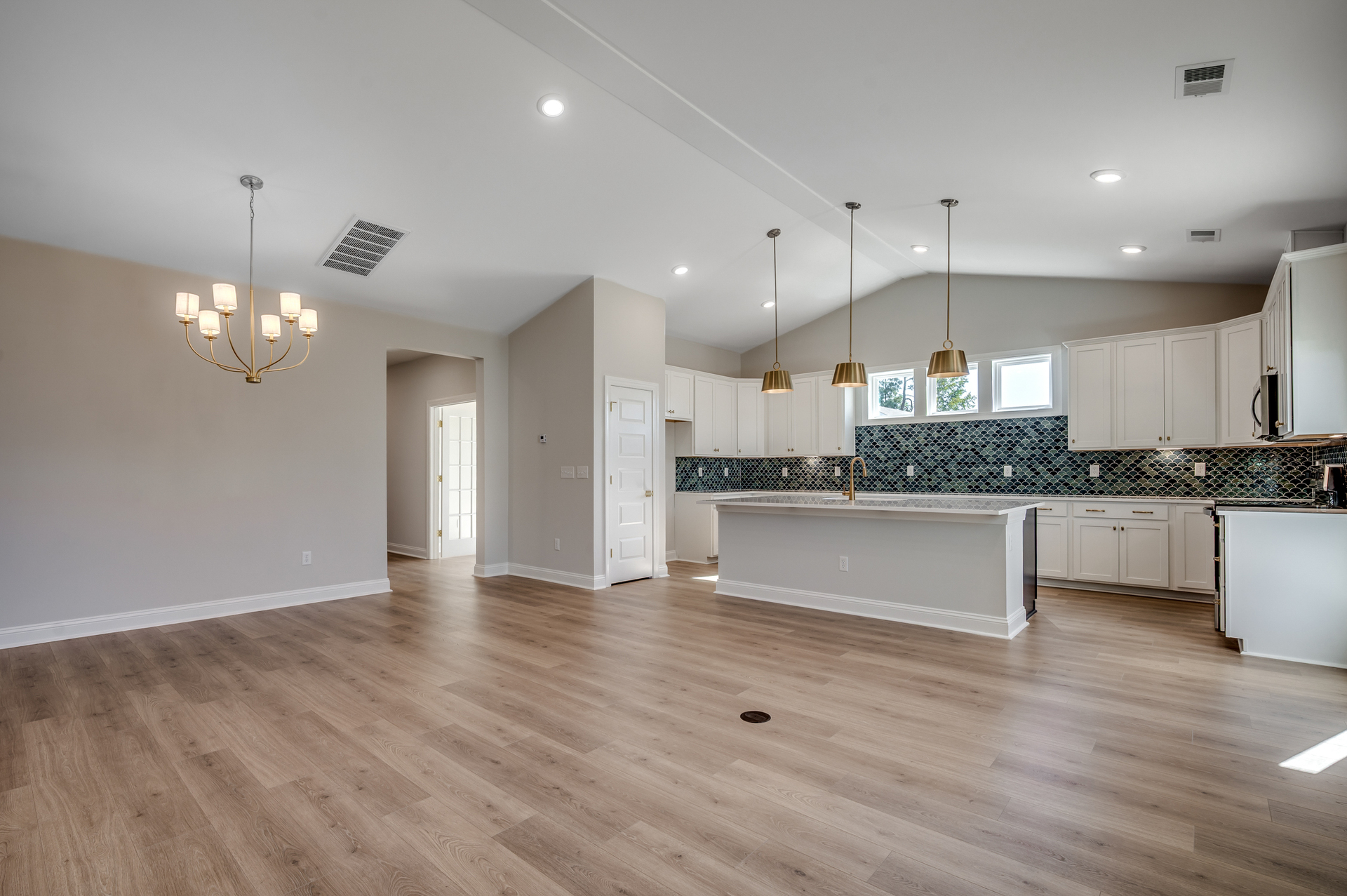 open-concept area with large island, gold fixtures and blue backsplash 