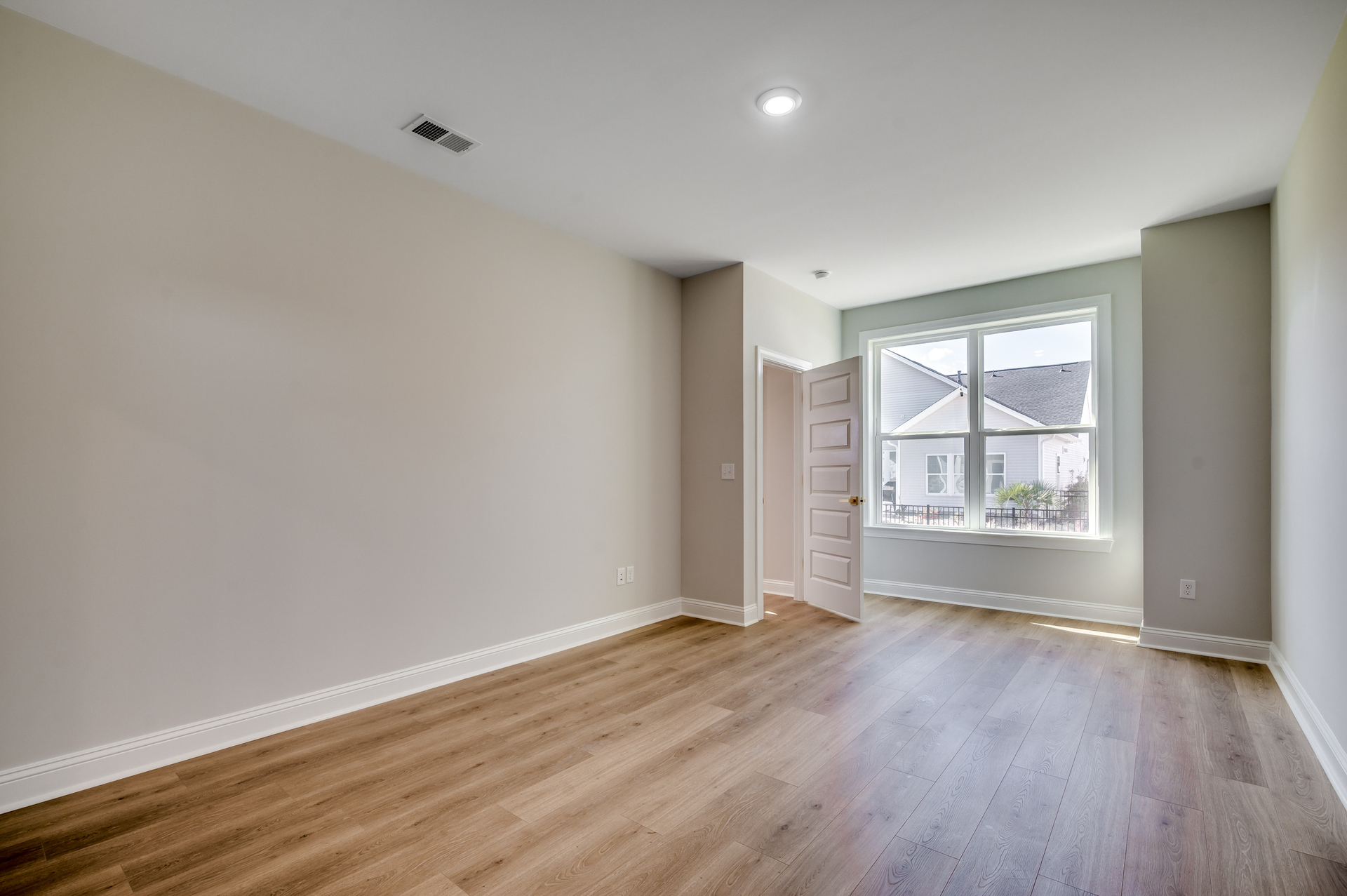spacious room with light hardwood flooring and large windows filling the room with natural light 