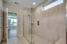 spacious spa-inspired walk-in shower with gold hardware, tiled flooring and tiled walls