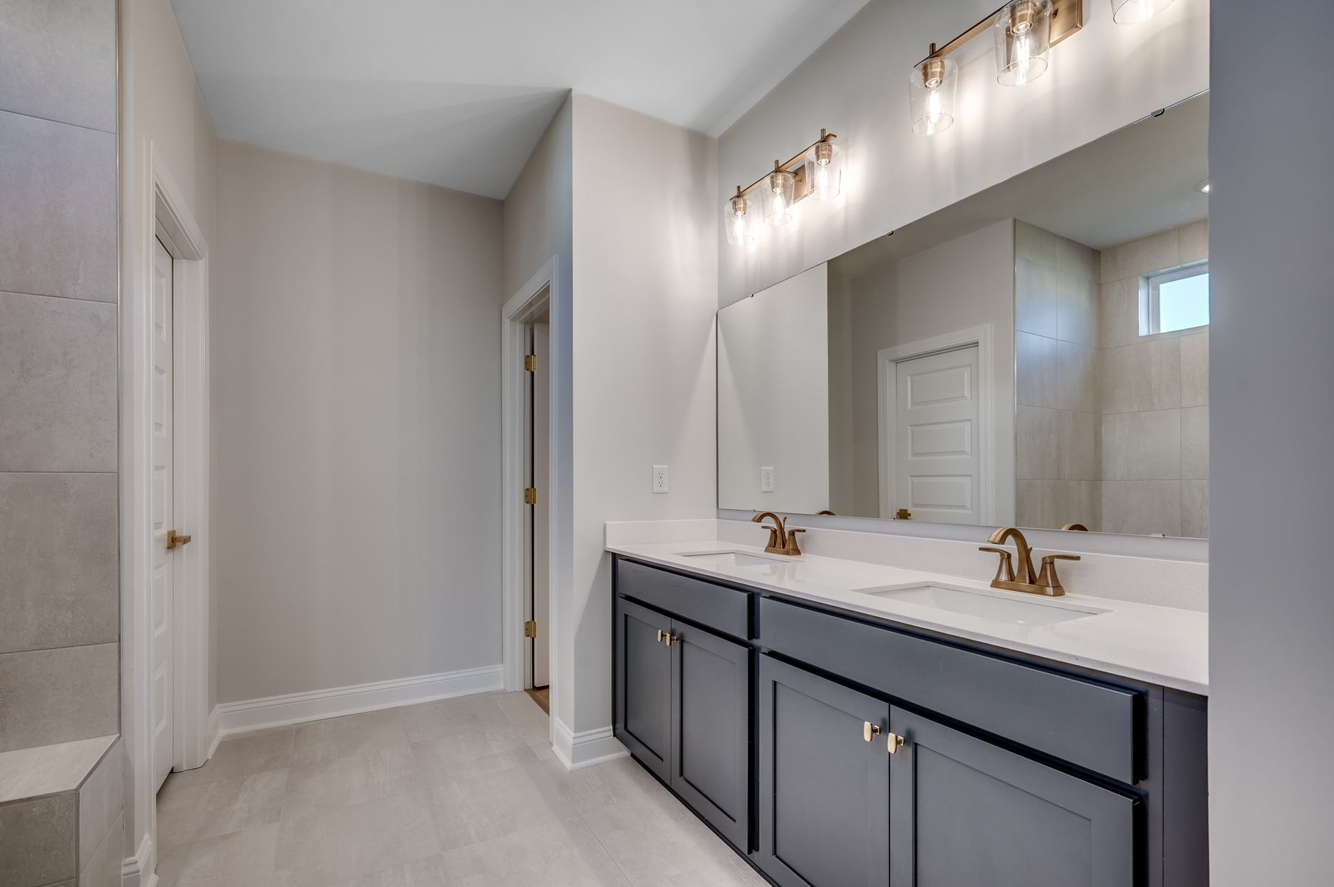 dark blue double vanity with gold hardware, matching fixtures, and sleek tile flooring